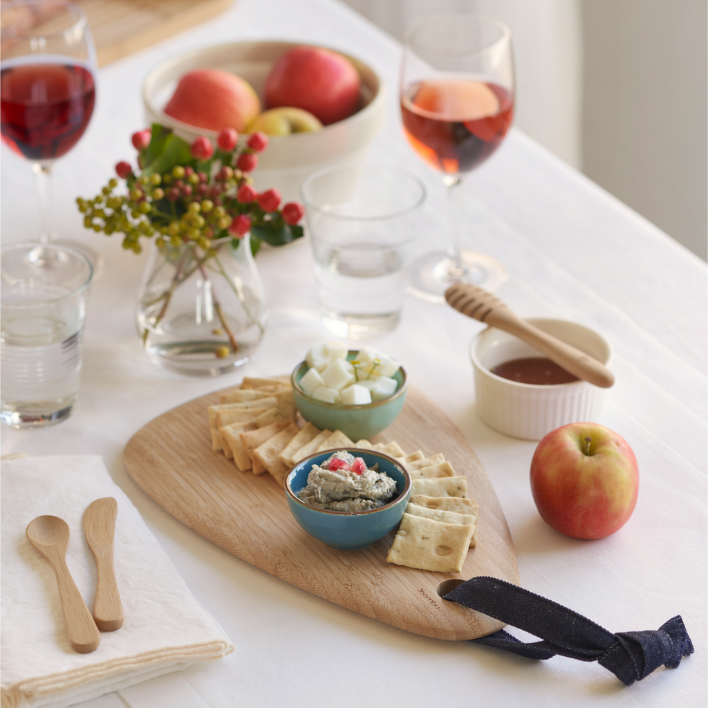 Artisan Droplet Board with crackers and spread. A bamboo honey dipper, spreader, and teaspoon are nearby for serving.