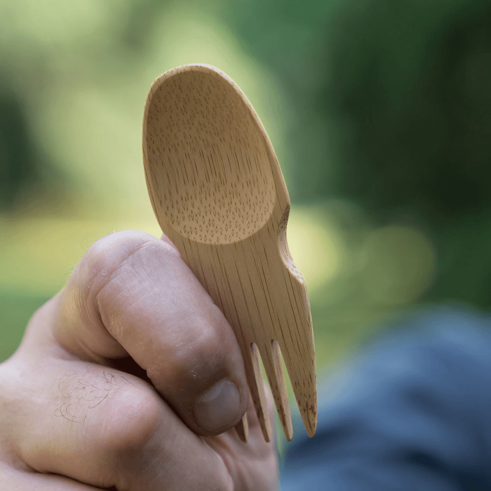 A person holds a spork in their outstretched hand.