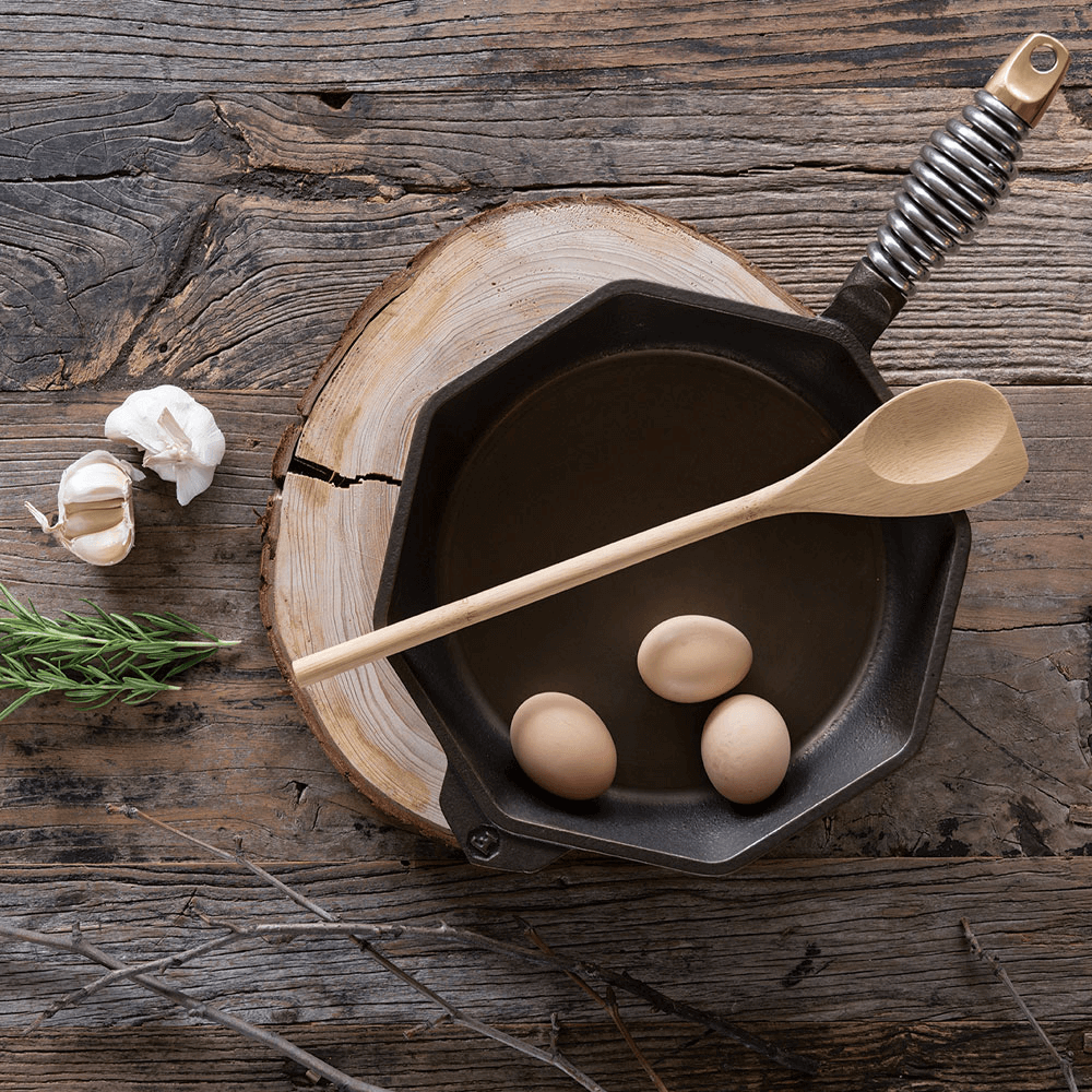 A bamboo Spoontula rests atop a Finex cast iron pan.