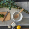 A Bamboo Serving Spoon rests in a mixing bowl. A cutting board and items for garnish are nearby. 