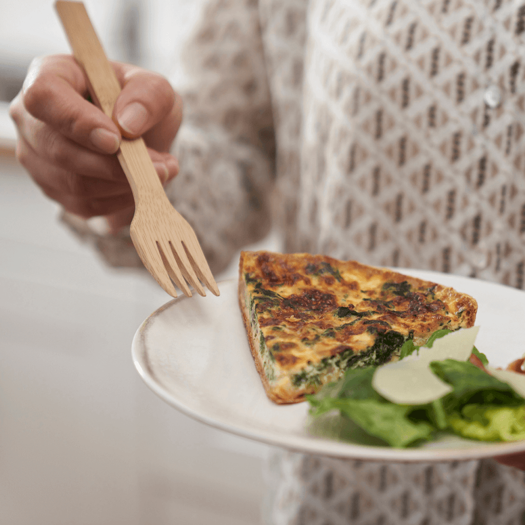 A person eats their meal using a reusable bamboo fork. bambu