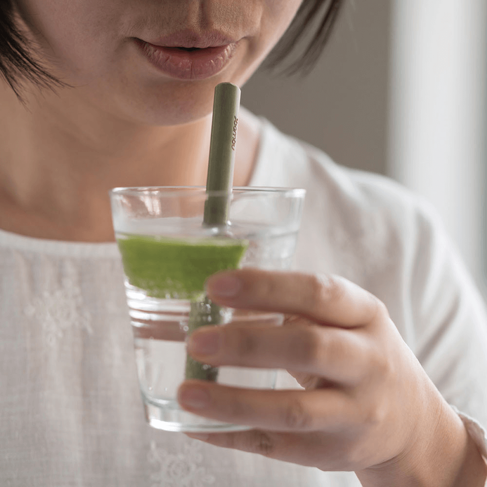 A person is about to take a sip of water through a Reusable Short Bamboo Straw.