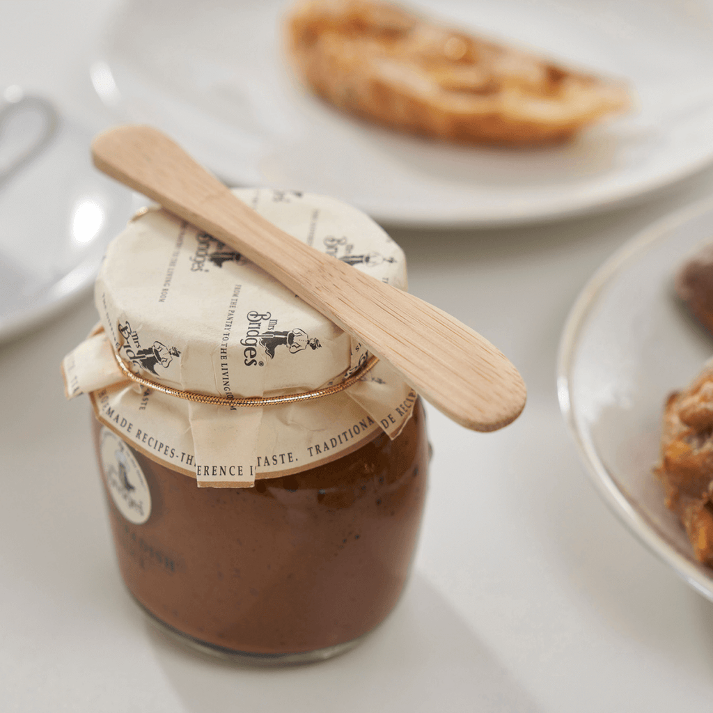 A Mini Bamboo Spreader rests atop a jar of jam. bambu