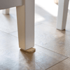 A Bamboo Tippy Table Wedge is under a wobbly table leg.