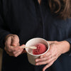 A person in a dark blue shirt eats a scoop of frozen dessert with a Veneerware® 4" Tasting Spoon - bambu