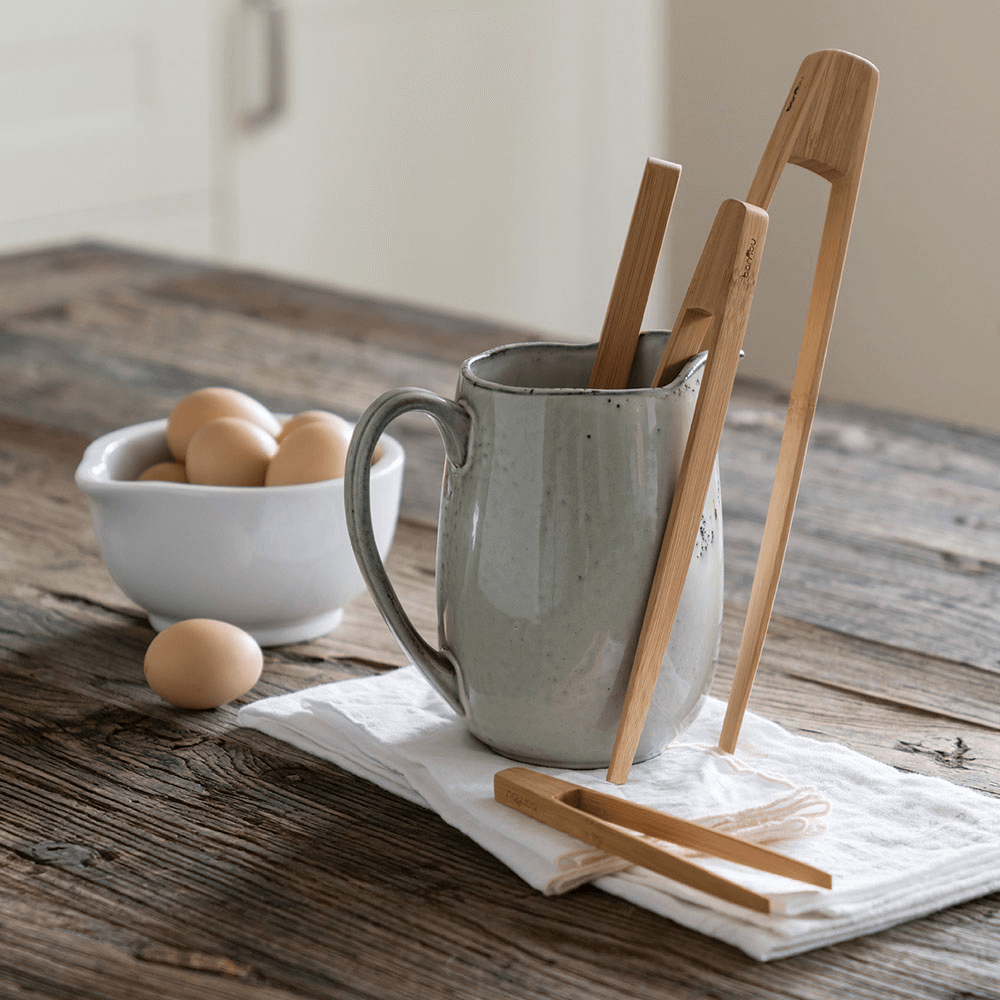 A Tongs Set (Large, Small and Tiny) is displayed in crock. There is a bowl of eggs in the background.