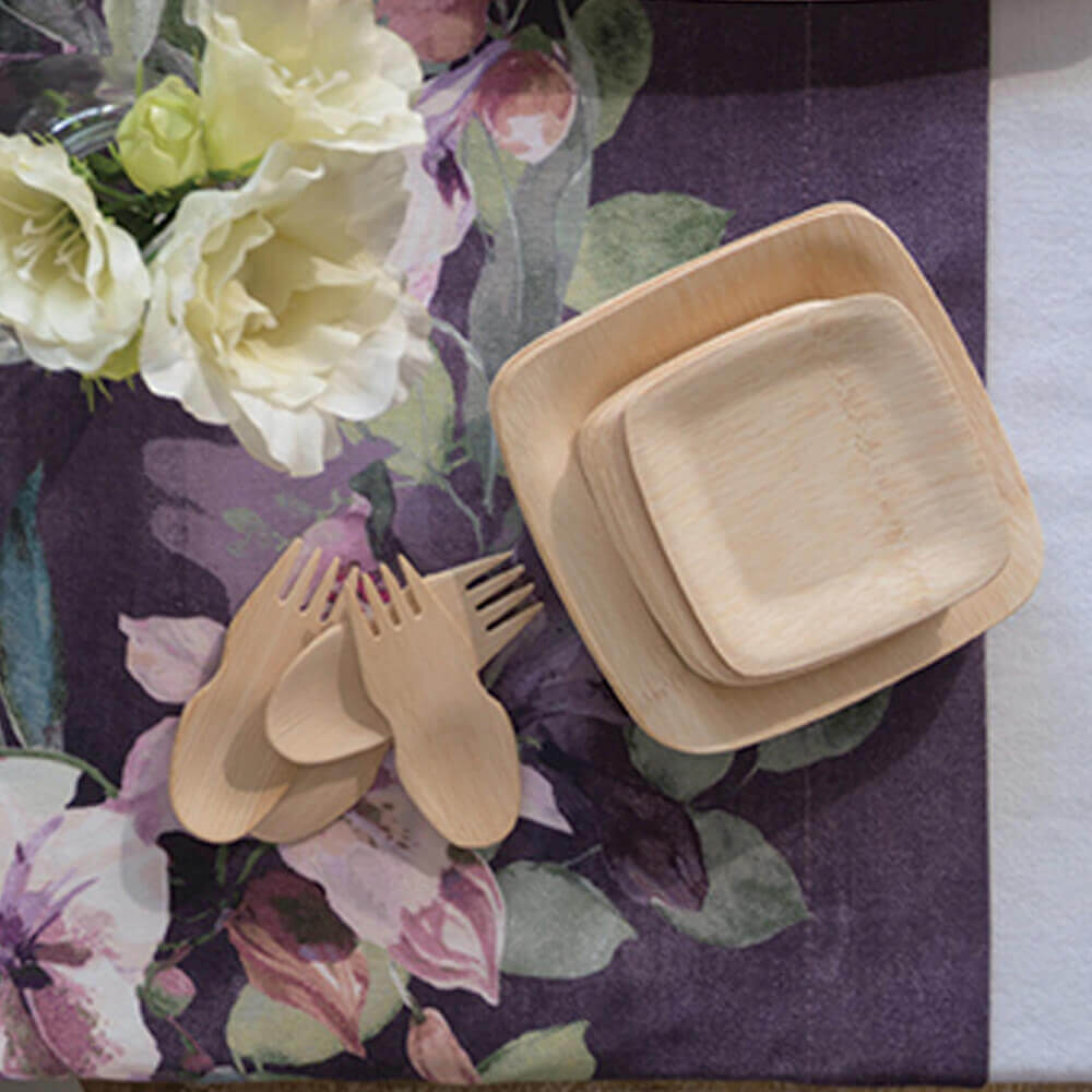 A stack of 3.5" and 5" Veneerware plates are on a table nest to a small pile of Veneerware Sporks.