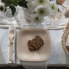 A 7" Veneerware Square plate is on a table. There is a multigrain bread slice on the plate.